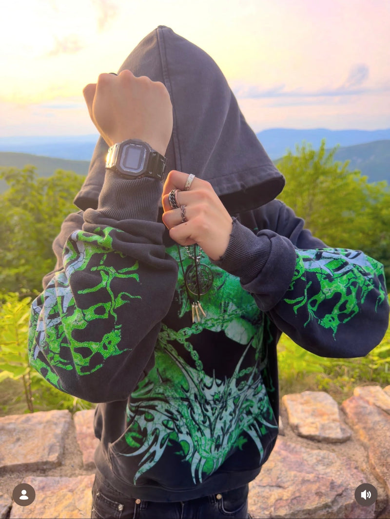 A dark square watch styled with a green graphic hoodie outdoors