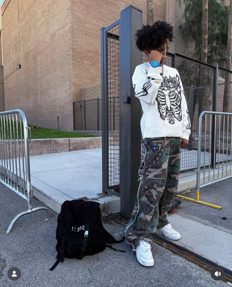 A blue watch styled with a white skeleton-print top and camouflage pants