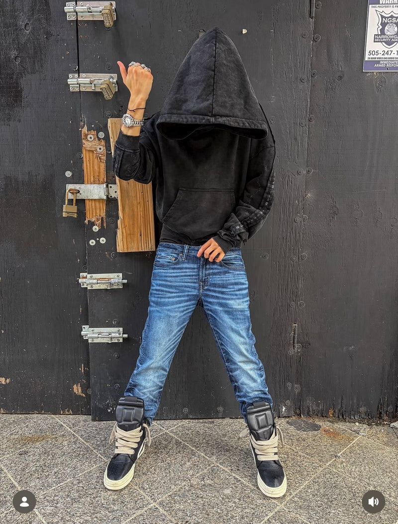 A silver watch styled with a black hoodie and blue jeans